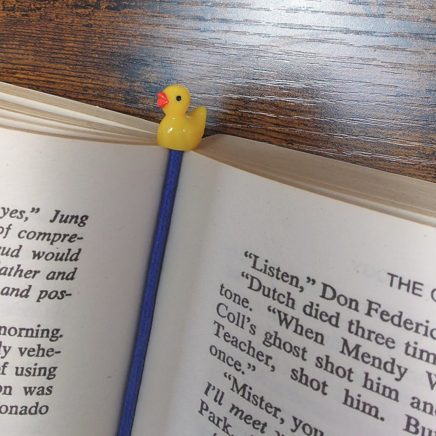 Open book with a yellow rubber duck bookmark on a wooden surface